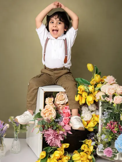 A close-up of pure joy. The boy's expressive, happy face is the centerpiece of this shot, surrounded by the beautiful and creative floral refrigerator prop.