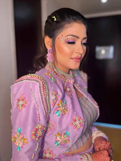 A close-up of the purple-toned eye makeup and the delicate face studs.