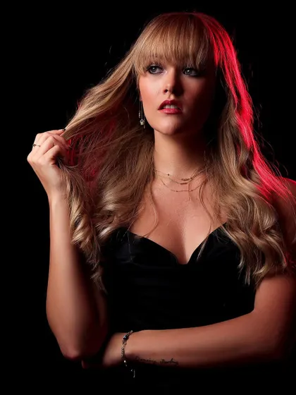 A portrait using a red backlight to create a vibrant rim light effect. This technique makes the model stand out against the black background and adds a touch of drama.