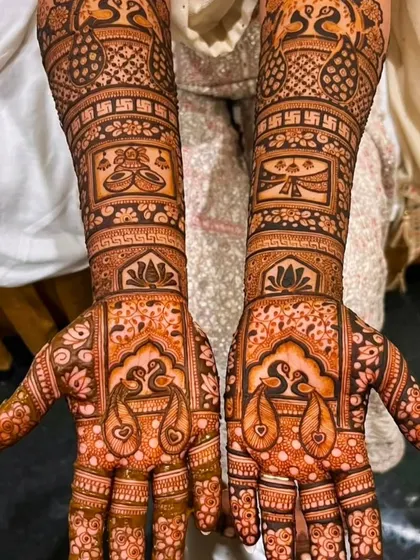 This design features peacocks on the palms and auspicious symbols like the swastika and kalash on the arms, perfect for a traditional bride.