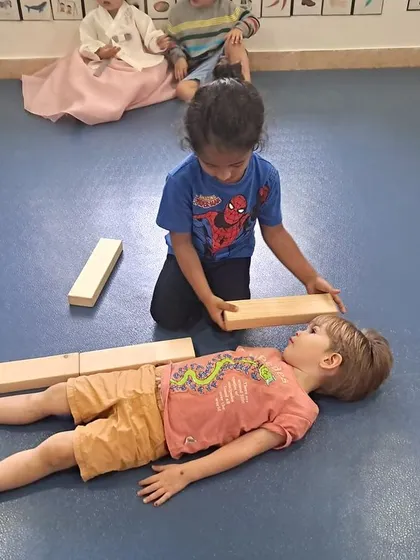 Another pair of students engaged in the "How tall am I?" activity, using blocks to understand the concept of height in a hands-on, memorable way.