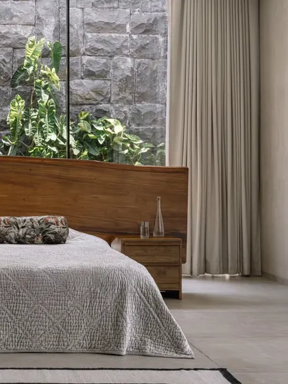 The bed in the master suite is positioned to offer a direct view of the private courtyard. The full-height window and sheer curtains allow for a soft, diffused light to fill the room.