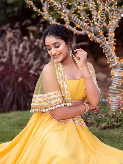 The model seated in the yellow lehenga, creating a beautiful picture against a fairy-lit tree.