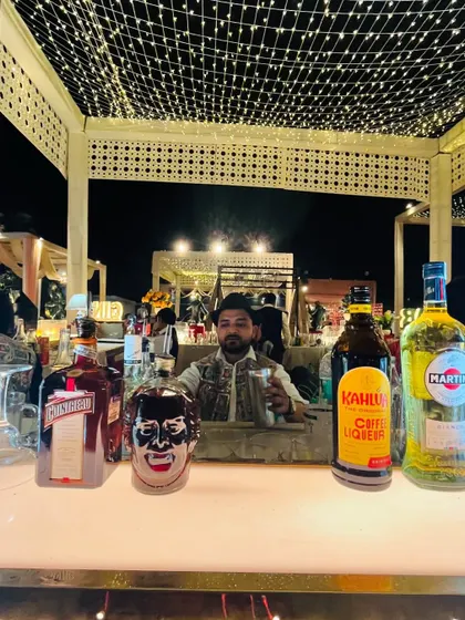One of our bartenders takes a moment behind the bar at a beautifully lit outdoor evening event.