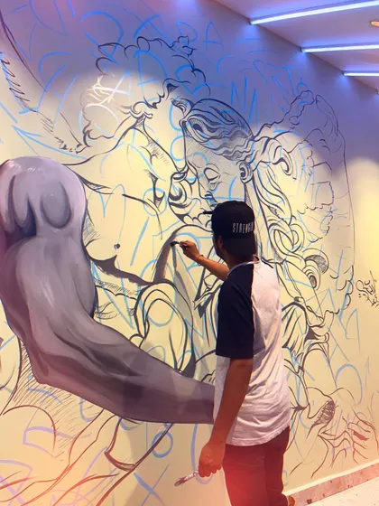 A low-angle shot of me working on the angelic couple mural. This perspective emphasizes the size of the artwork and the focus required to paint such a detailed piece.