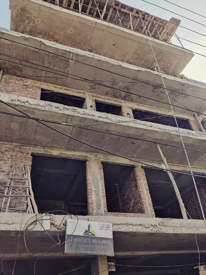 A building under construction, with our firm's board displayed prominently. This shows an early stage, with the brickwork and concrete structure exposed.
