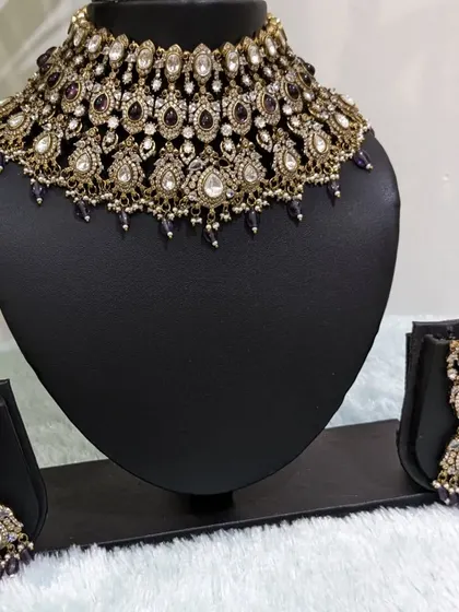 This Victorian-style choker in a unique purple color is a captivating piece. It's shown here with two different earring styles, a stud and a jhumka, to show its versatility.