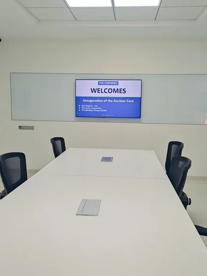 A clean, minimalist conference room at the TVS Auction Centre. The design prioritizes functionality with a large table, comfortable seating, and a wide-screen display, creating a distraction-free environment for meetings.