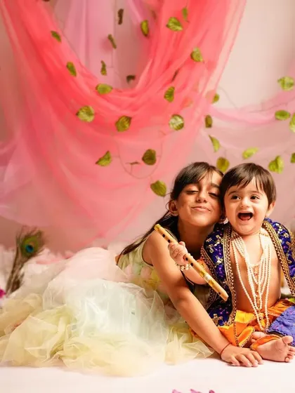 A joyful moment between siblings during a Janmashtami themed shoot. The older sister, dressed as Radha, shares a laugh with her little brother, our "Makhan Chor."