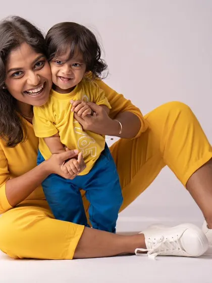 A mother and her nine-month-old son, sharing a happy and playful moment. Their matching yellow outfits add a bright and cheerful touch.