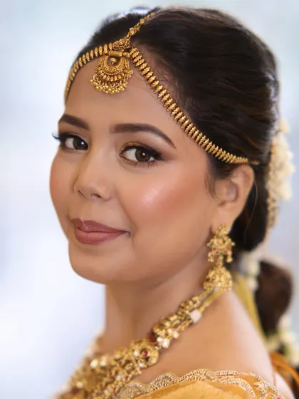 A close-up of the South Indian bride, showing how the neat hairstyle complements her radiant makeup and traditional gold jewelry.