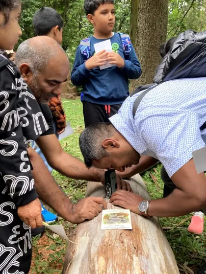 Even the adults get curious. A father joins his child in peering through a magnifier to inspect fungi on a log, sharing in the joy of discovery.