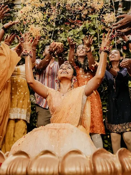 A beautiful moment of celebration as friends shower the bride with flower petals during her Haldi.