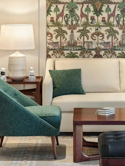 A close-up of the living room at Max128, focusing on the green accent chair and patterned wallpaper.