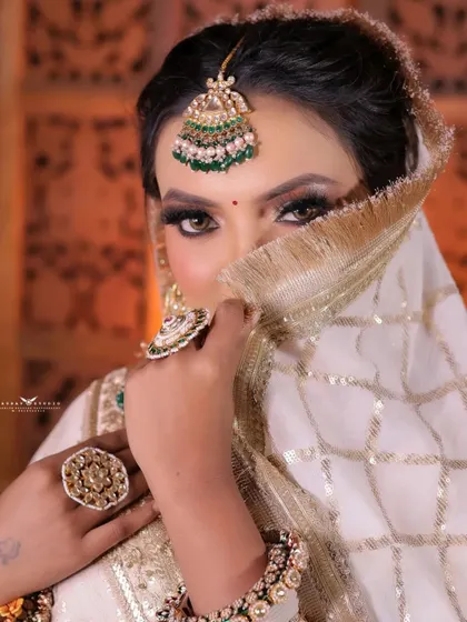 A playful yet elegant shot of the bride covering her face with her dupatta. This classic pose is given a modern twist with her direct, confident gaze.
