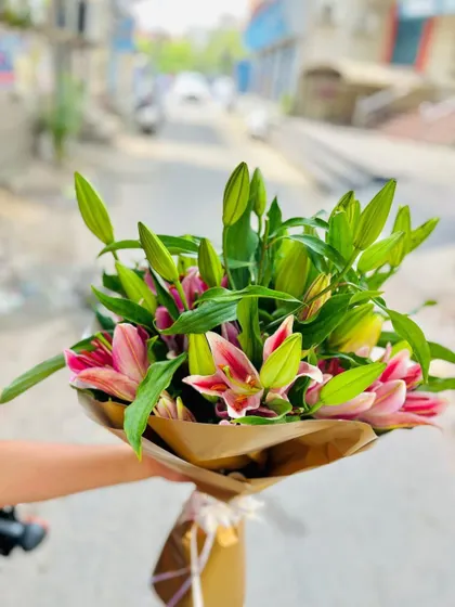This bouquet showcases the simple beauty of fresh lilies. The pink lily buds are just about to bloom, arranged with their natural green leaves and wrapped in simple brown kraft paper for a fresh, rustic, and elegant look.