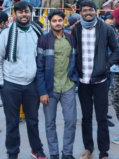 **Three Friends in the Himalayas.** A candid shot of three travelers enjoying their pilgrimage, with the Badrinath temple town behind them.