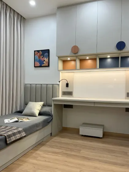 A shared bedroom designed for two, with space-saving single beds and a long study desk in between. The design uses color blocking in burnt orange, blue, and yellow to define spaces.