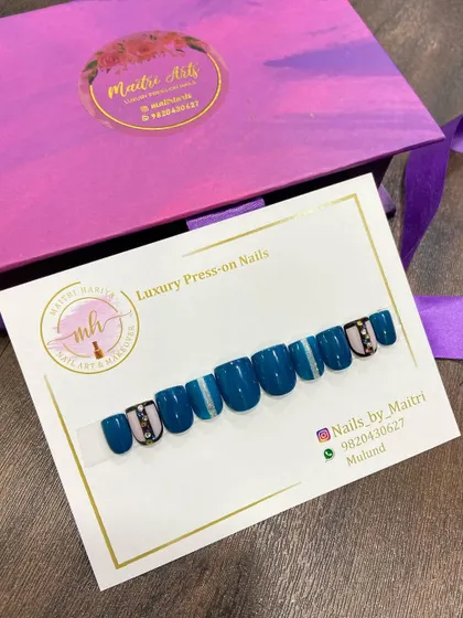 A bold and beautiful press-on set in a deep teal color, with striped and jeweled accent nails.
