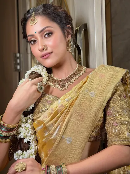 A beautiful close-up showcasing the soft, shimmering eye makeup and flawless skin. This look is a perfect balance of tradition and modern elegance for the South Indian bride.