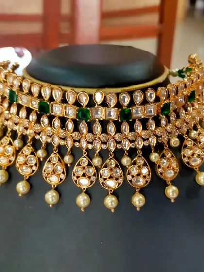 A close-up of a stunning layered Kundan choker with green stones and pearl drops. This piece is available for rent and is perfect for a bridal or bridesmaid look.