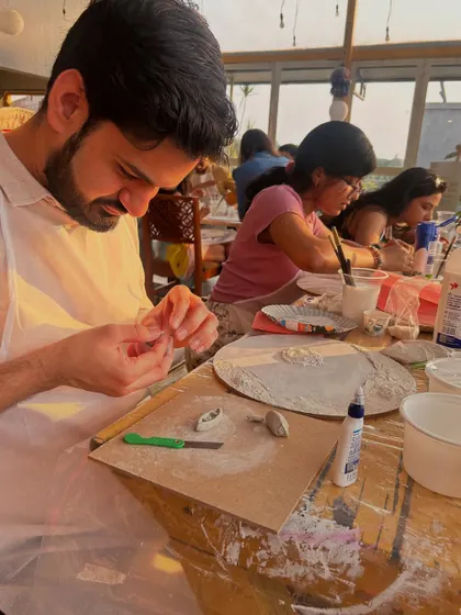A participant creating texture on his beach-themed artwork. The use of different materials adds a realistic, sandy feel.