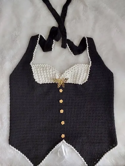 A flat-lay of the Belladonna Top, showing the full design with its halter straps, corset-style body, and delicate scalloped edging.