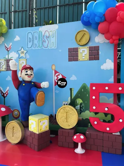 Power up! This Super Mario themed backdrop is perfect for photos, featuring a 3D Mario, a light-up number '5', and iconic elements like question blocks, coins, and mushrooms.