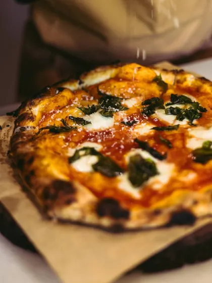 A final dusting of parmesan cheese over a freshly baked pizza. This adds a last touch of salty, nutty flavor that completes the dish.