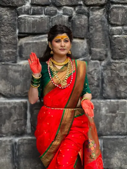 A shot from the music video showing Savaniee in a devotional pose. The red-stained hands and bold makeup are key elements of this traditional look.