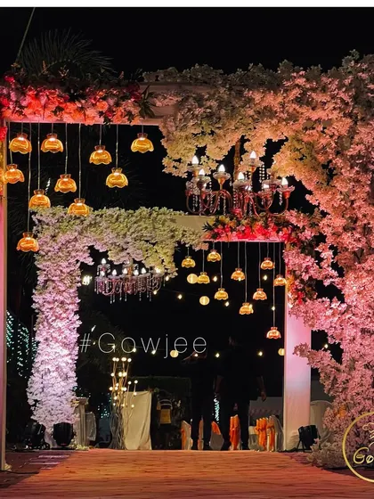 A stunning entrance arch adorned with pink cherry blossoms and hanging lamps.