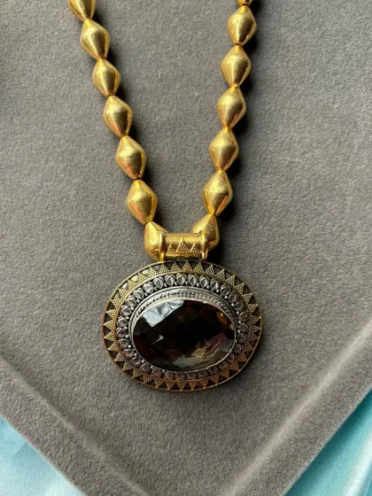 A premium pure silver necklace with a gold-plated finish. This piece features a large, oval smoky quartz stone set in a dual-tone frame, combining modern design with classic materials.