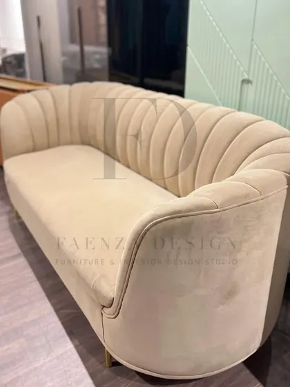 This sofa features a unique scalloped backrest and is upholstered in a soft beige velvet. The clean lines and subtle gold-finished legs make it a sophisticated and contemporary choice.