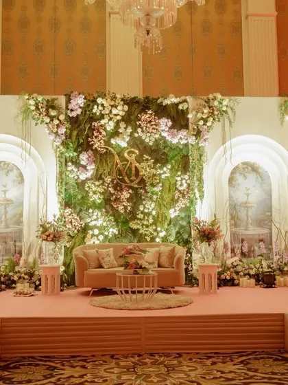 A different view of the indoor garden stage, showing how the elevated platform and soft pink flooring made the romantic floral backdrop even more of a centerpiece.