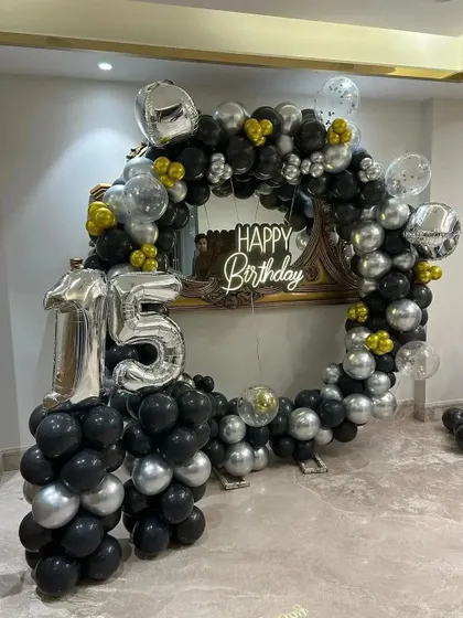 A cool and modern ring setup for a 15th birthday, using black, silver, and gold balloons.