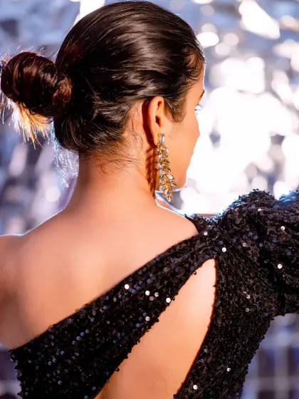 A detail shot of the back of a black sequined dress. This highlights the design's unique cut and the way the light catches the material, perfect for a designer lookbook.