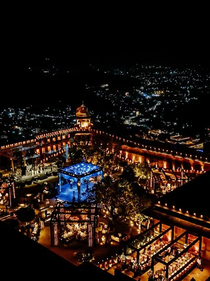 An incredible aerial view of the celebration at Jaigarh Fort, with the entire courtyard lit up, and a central blue-lit structure creating a stunning focal point.