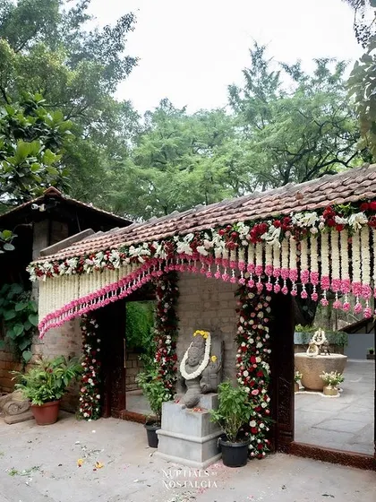 The entrance gates adorned with garlands of white and red flowers, creating a festive welcome.