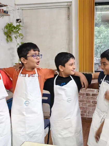 The best part of a pottery party is the fun you have with your friends. These boys are sharing a laugh after their creative session, proudly wearing their aprons.