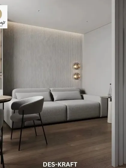 This shot highlights the comfortable living area adjacent to the kitchen, featuring a plush grey sofa and textured wall panels for added warmth.