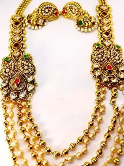 A long, layered antique necklace with pearl and gold beads. This rani haar style piece is perfect for creating a grand, traditional look for a wedding.