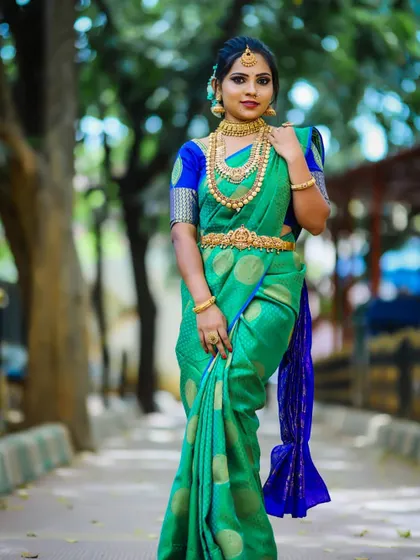 A full-length view of a stunning bride in a green silk saree. This showcases the complete package: HD makeup, intricate hairstyling, traditional jewellery, and expert saree draping.