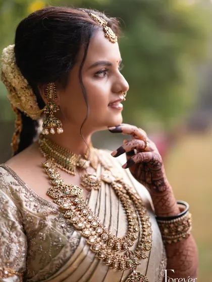 A profile shot showcasing the beautiful harmony of makeup, hair, and jewellery. The soft updo is adorned with fresh flowers, a classic touch for a South Indian bride.