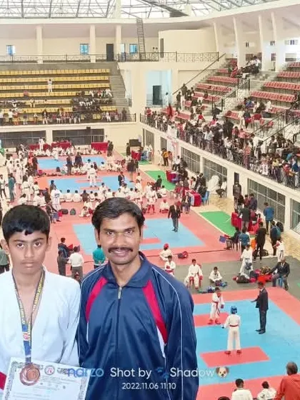 A wide-angle shot showing my students and me against the backdrop of the bustling state-level karate championship.