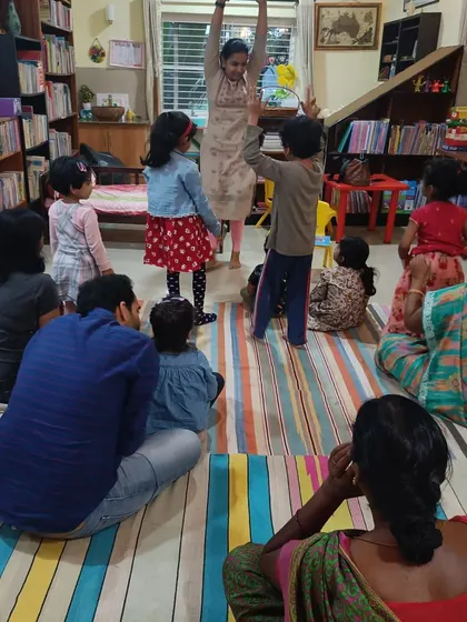 The storyteller leads an interactive movement activity before the craft session begins, getting the wiggles out and preparing the children to focus.