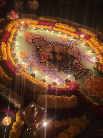 A rangoli of the Goddess, lit with many lamps, creating a divine glow.