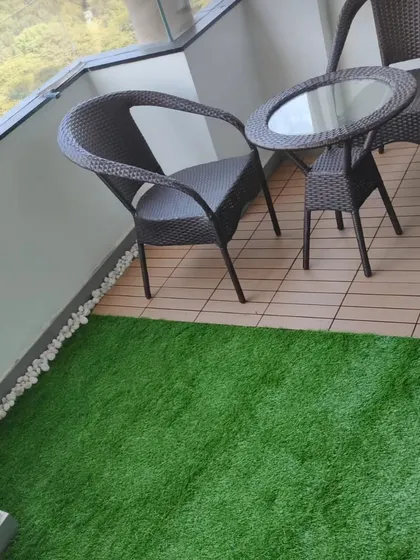 This small balcony uses a mix of materials for a clean look. I installed a section of artificial grass next to wood-look deck tiles, creating a perfect spot for a small table and chairs.