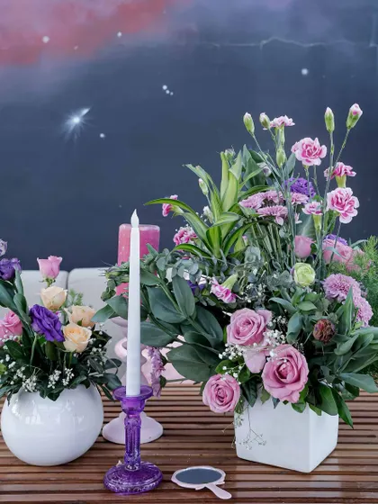 A beautiful floral centerpiece with a mix of roses and carnations, set against a backdrop of a hand-painted starry sky panel.
