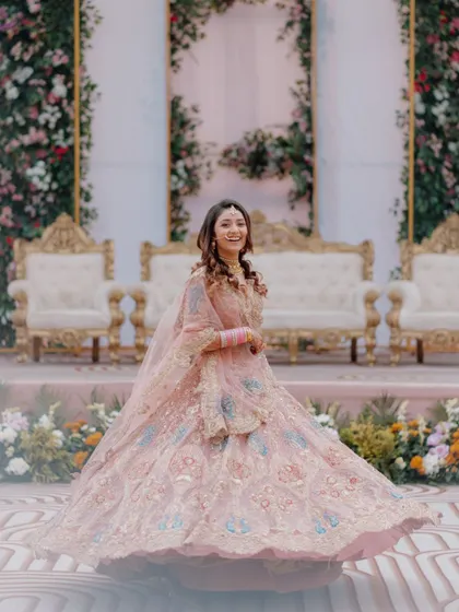 A full-length shot of the bride twirling in her magnificent pink lehenga, capturing the grandeur of her outfit and her joyful spirit.