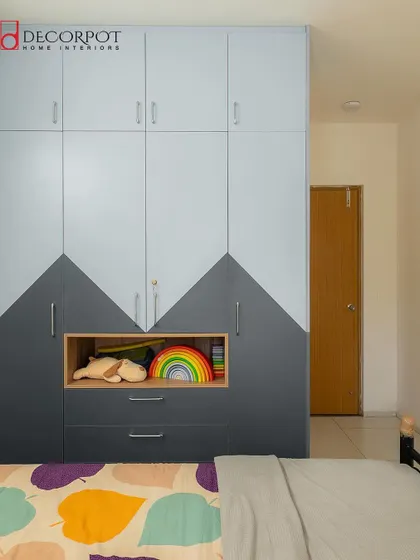 A modern two-tone hinged wardrobe for a kid's room, featuring a geometric design in grey and white. The open niche and drawers provide a mix of display and concealed storage.